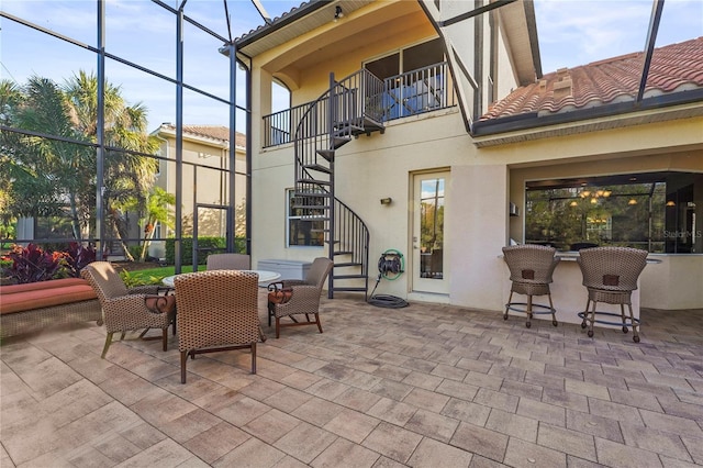 view of patio featuring stairs, outdoor dining area, a lanai, and a balcony