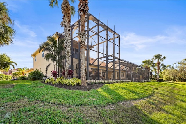 back of property with a lanai, a lawn, and stucco siding