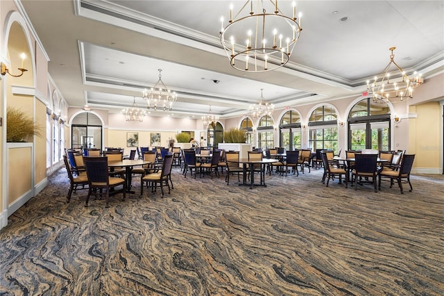 carpeted dining space featuring ornamental molding, a tray ceiling, a notable chandelier, and arched walkways