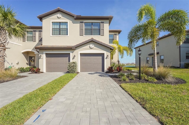 view of front of home featuring a garage, decorative driveway, and stucco siding