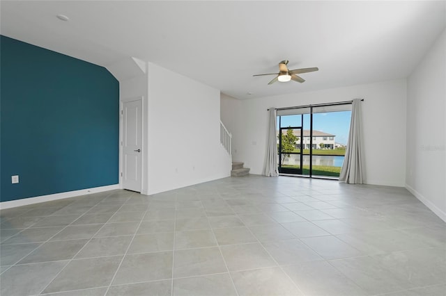 empty room featuring light tile patterned floors, ceiling fan, stairway, and baseboards
