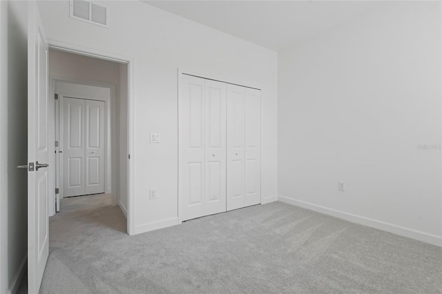 unfurnished bedroom featuring carpet floors, baseboards, a closet, and visible vents