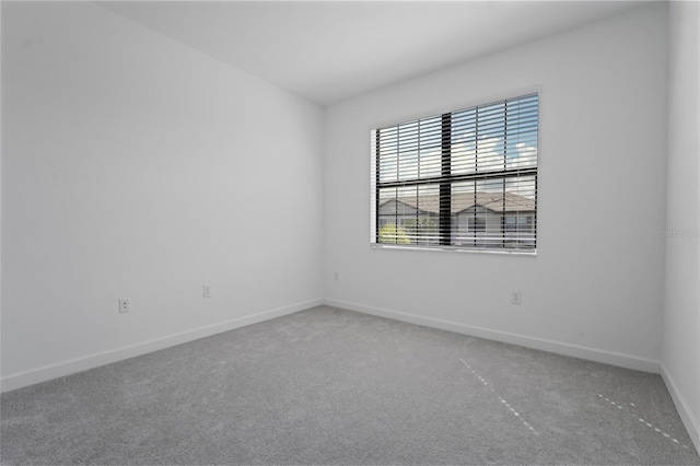 carpeted spare room featuring baseboards