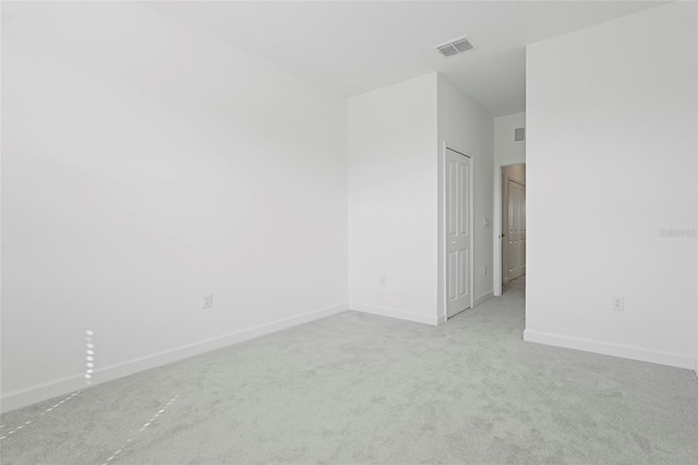 carpeted spare room featuring visible vents and baseboards