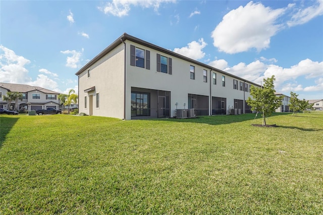 back of property with central air condition unit, a lawn, and stucco siding