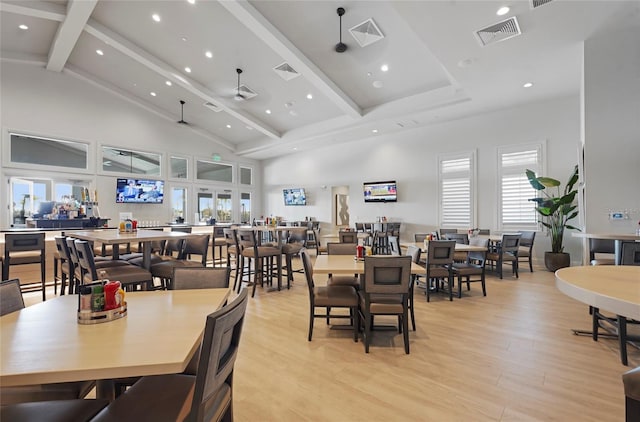 dining room featuring ceiling fan, high vaulted ceiling, beamed ceiling, visible vents, and light wood finished floors