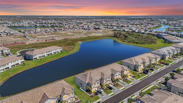 aerial view at dusk with a residential view and a water view