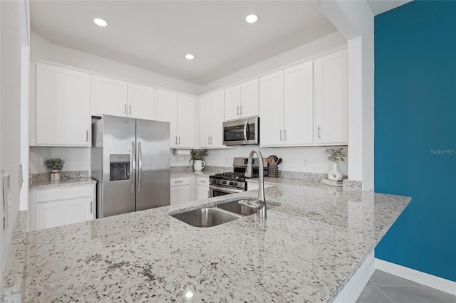 kitchen with stainless steel appliances, tile patterned flooring, light stone countertops, and white cabinetry