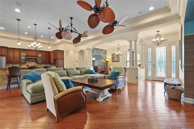 living room with wood-type flooring, a raised ceiling, and ornate columns