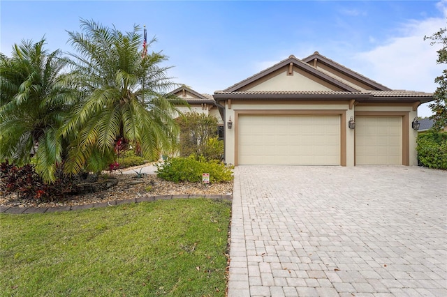 view of front of home with decorative driveway, a tile roof, an attached garage, and stucco siding