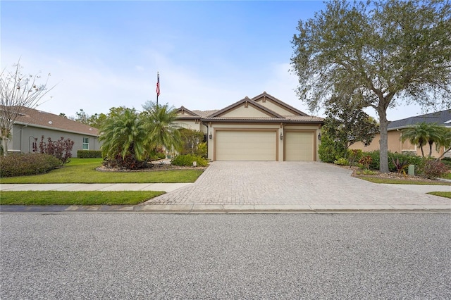 view of front of property featuring a garage, a tiled roof, decorative driveway, a front yard, and stucco siding