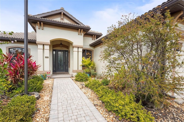 entrance to property with a tile roof and stucco siding