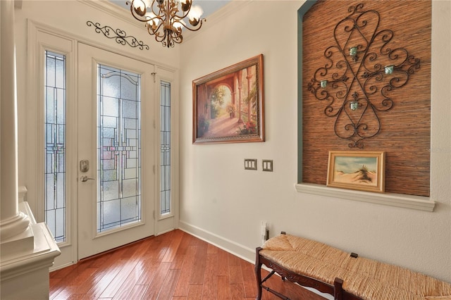 entryway with crown molding, a notable chandelier, baseboards, and hardwood / wood-style flooring