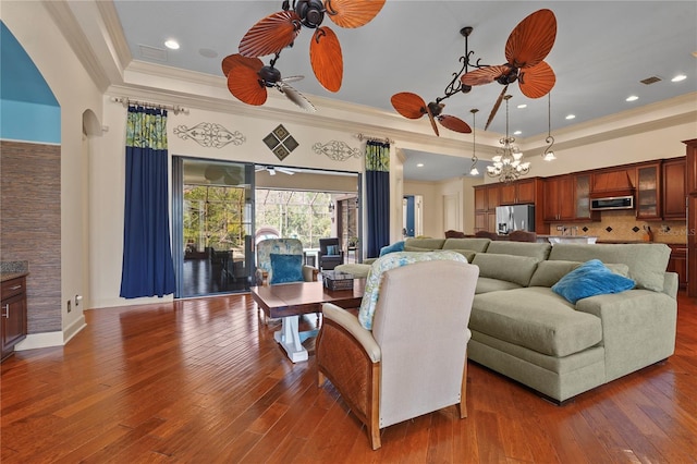 living area featuring visible vents, ornamental molding, a raised ceiling, and hardwood / wood-style floors