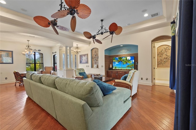 living room featuring visible vents, arched walkways, wood-type flooring, an inviting chandelier, and ornate columns