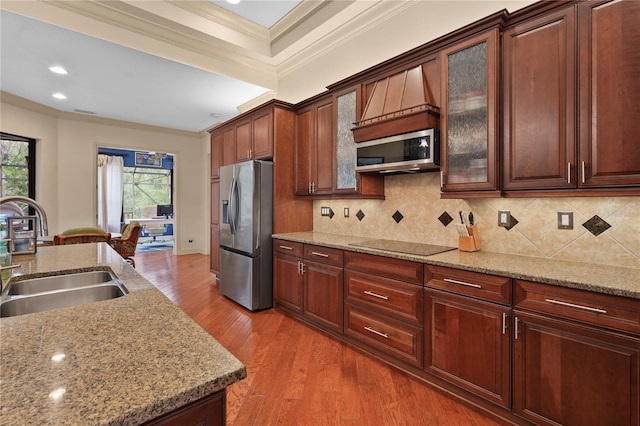 kitchen with stainless steel appliances, wood finished floors, a sink, ornamental molding, and backsplash