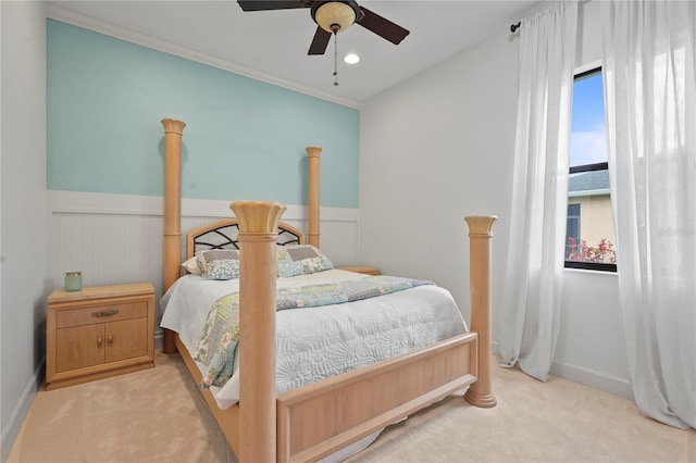 bedroom featuring ceiling fan, wainscoting, and light colored carpet