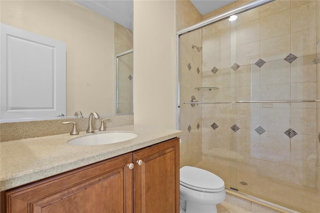 bathroom with vanity, a shower stall, and toilet