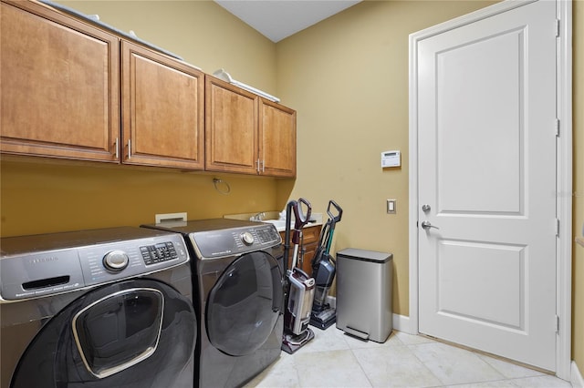 clothes washing area featuring cabinet space, washing machine and dryer, baseboards, and light tile patterned flooring