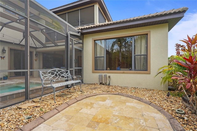 view of home's exterior with an outdoor pool, a tile roof, a lanai, a patio area, and stucco siding