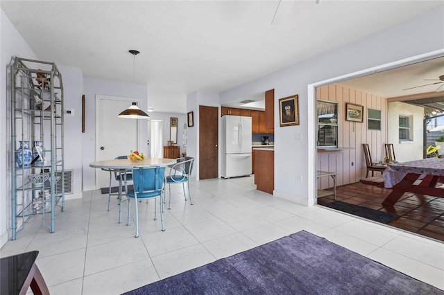 dining area featuring light tile patterned floors, a ceiling fan, visible vents, and wood walls