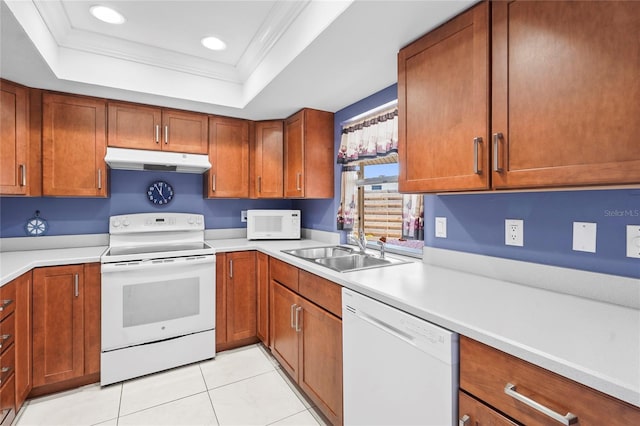 kitchen with under cabinet range hood, a tray ceiling, a sink, white appliances, and crown molding