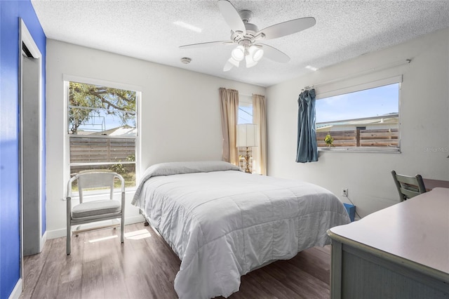 bedroom featuring ceiling fan, wood finished floors, and a textured ceiling