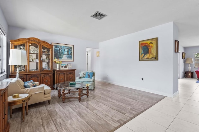 living area with baseboards, visible vents, and light wood finished floors