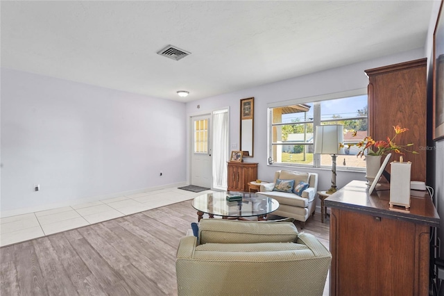 living room featuring wood finished floors, visible vents, and baseboards