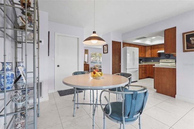 dining space with light tile patterned floors, visible vents, baseboards, and a tray ceiling