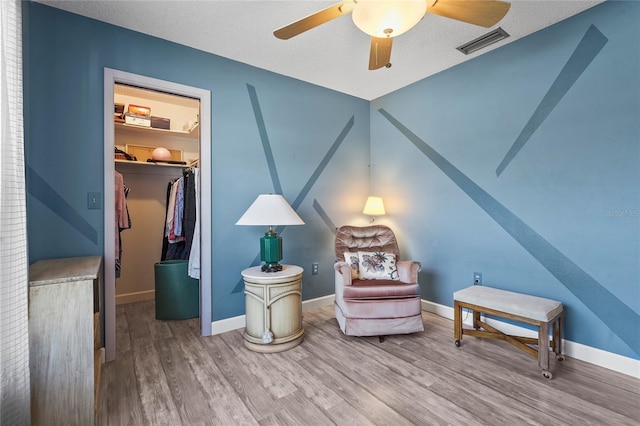 sitting room with visible vents, baseboards, and wood finished floors