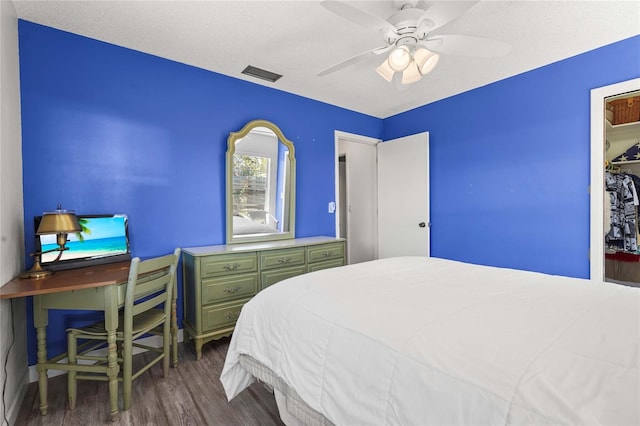 bedroom featuring dark wood finished floors, visible vents, a textured ceiling, and a ceiling fan