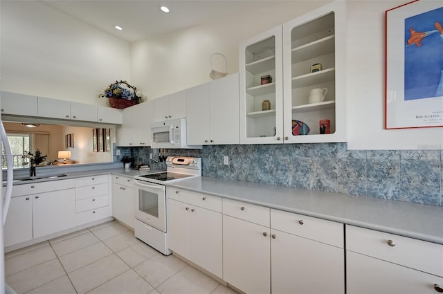 kitchen featuring light tile patterned flooring, white appliances, a high ceiling, white cabinetry, and backsplash