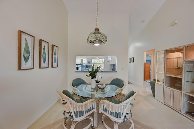 dining area featuring high vaulted ceiling, light colored carpet, and baseboards