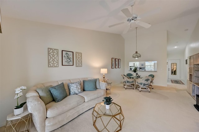 carpeted living area with high vaulted ceiling and ceiling fan