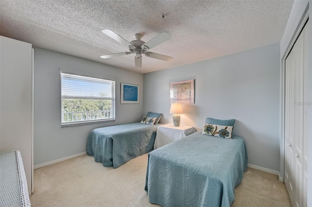 bedroom with a textured ceiling, carpet flooring, a ceiling fan, baseboards, and a closet