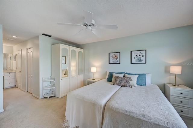 bedroom with a textured ceiling, light carpet, a ceiling fan, visible vents, and multiple closets