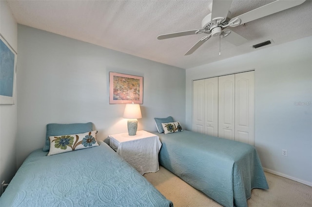 carpeted bedroom with baseboards, visible vents, ceiling fan, a textured ceiling, and a closet