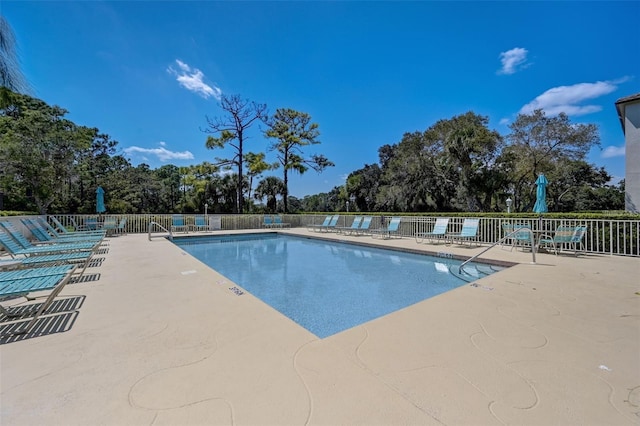 community pool with a patio area and fence