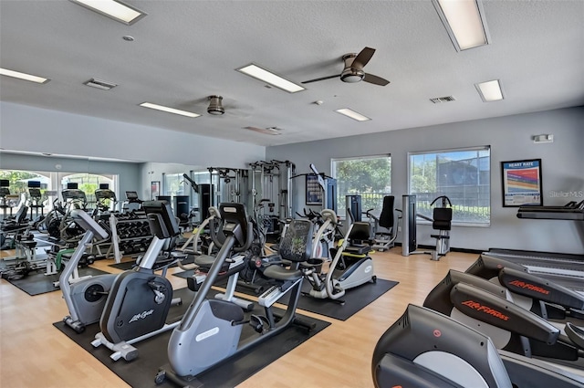 workout area with wood finished floors, visible vents, and a ceiling fan