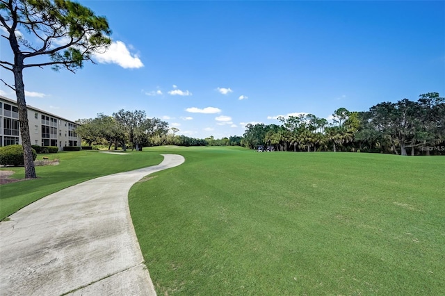 view of property's community with view of golf course and a lawn