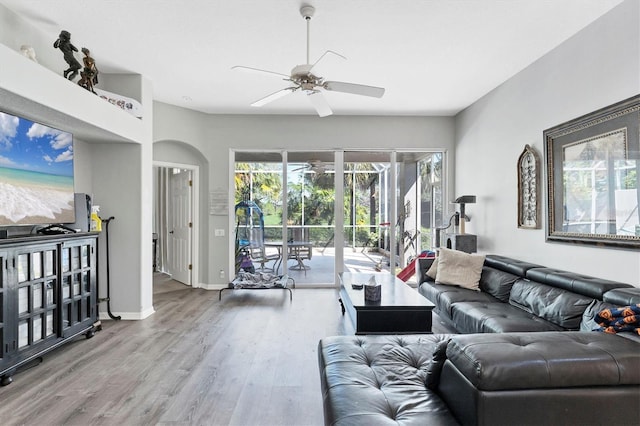 living area featuring baseboards, a ceiling fan, and wood finished floors