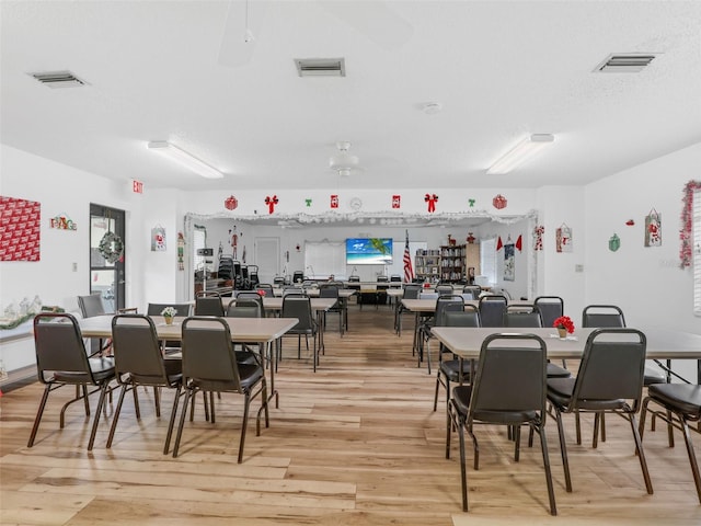 dining space with light wood-style floors, visible vents, and a textured ceiling