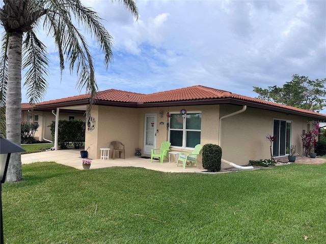 back of property featuring a yard, a tiled roof, a patio area, and stucco siding