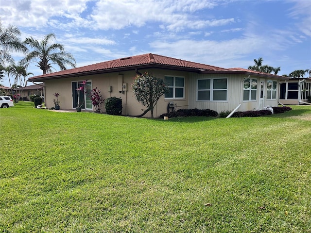 back of house featuring a lawn and a tile roof