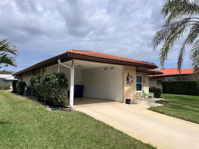 back of property featuring a yard, a tile roof, an attached carport, and stucco siding