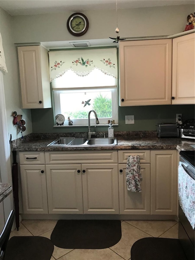 kitchen with light tile patterned floors, electric range, a sink, white cabinetry, and dark countertops