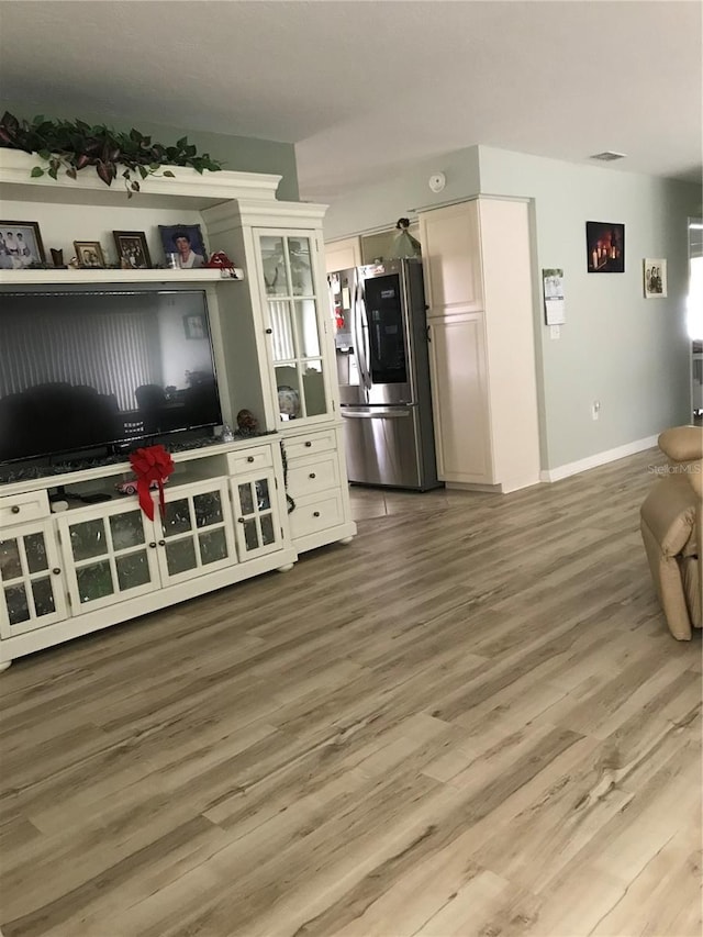 kitchen featuring visible vents, stainless steel refrigerator with ice dispenser, baseboards, and wood finished floors