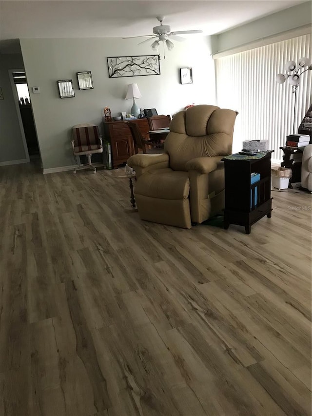 living room featuring dark wood-style floors, ceiling fan, and baseboards