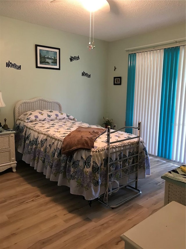 bedroom with ceiling fan, a textured ceiling, and wood finished floors